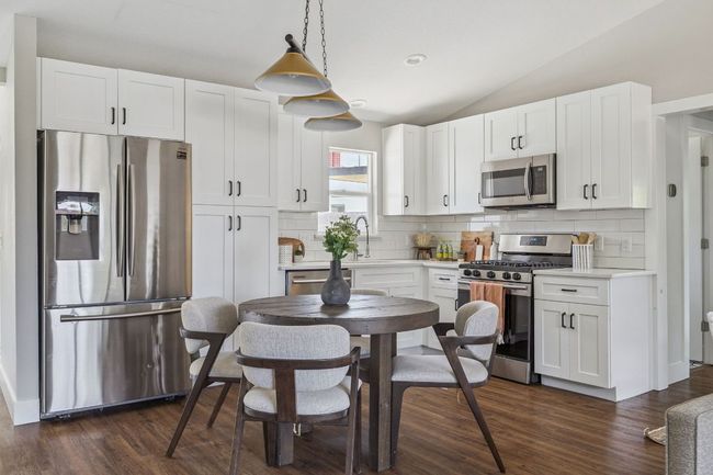 Kitchen featuring stainless steel appliances, backsplash, white cabinetry, dark wood-style floors, and vaulted​​‌​​​​‌​​‌‌​‌‌​​​‌‌​​‌‌​‌​​​​​‌ ceiling | Image 12