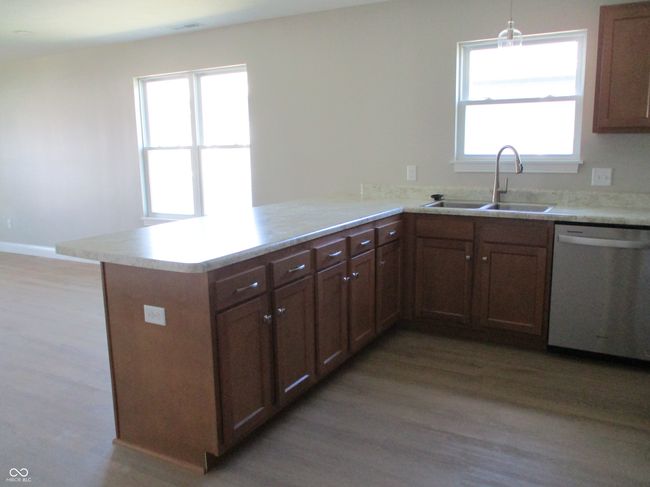 kitchen featuring a sink, light wood-style floors, stainless steel dishwasher, and a peninsula | Image 7