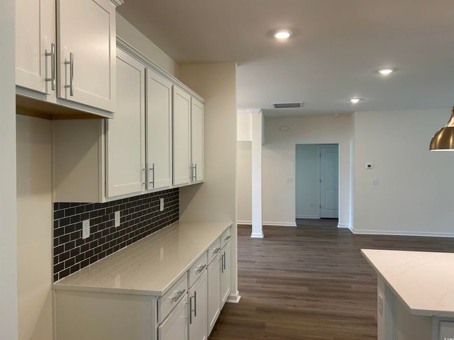 Kitchen featuring decorative backsplash, dark wood finished floors, white cabinets, recessed lighting, and baseboards | Image 10