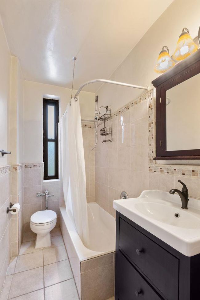Bathroom with tile walls, toilet, vanity, shower / bath combo, and tile patterned floors | Image 4