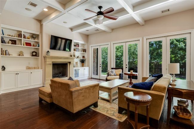 Living room with dark wood-type flooring, coffered ceiling, french doors, a fireplace with raised hearth, and beamed ceiling | Image 8