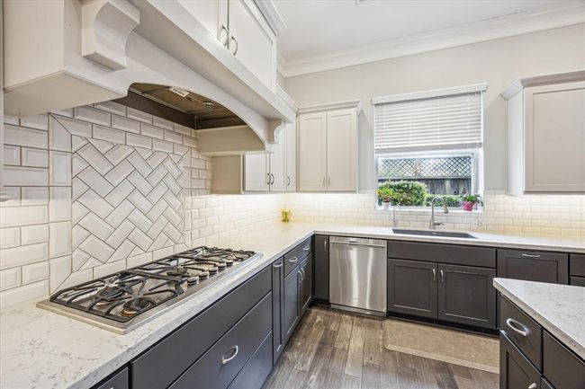 A six-burner gas cooktop has your home chef covered, and the stylish herringbone tile backsplash adds designer detail. | Image 14