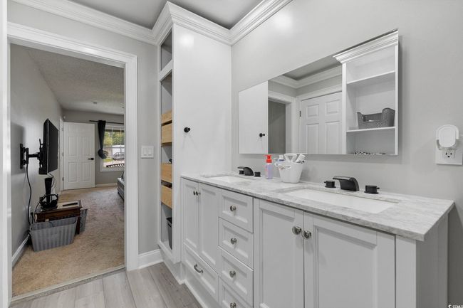 Ensuite bathroom featuring double vanity, wood finished floors, baseboards, and crown molding | Image 20