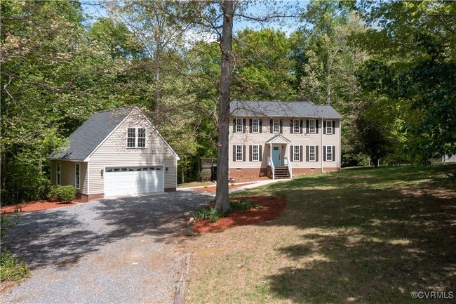 Colonial inspired home featuring gravel driveway, crawl space, an outdoor structure, a front yard, and a garage | Image 5