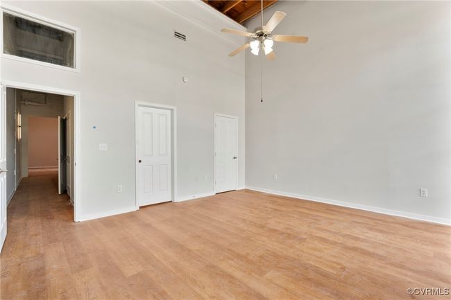 Spare room with a towering ceiling, light wood finished floors, ceiling fan, and beam ceiling | Image 13