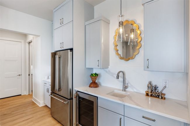 Kitchen featuring beverage cooler, high end fridge, light wood finished floors, hanging light fixtures, and decorative backsplash | Image 15