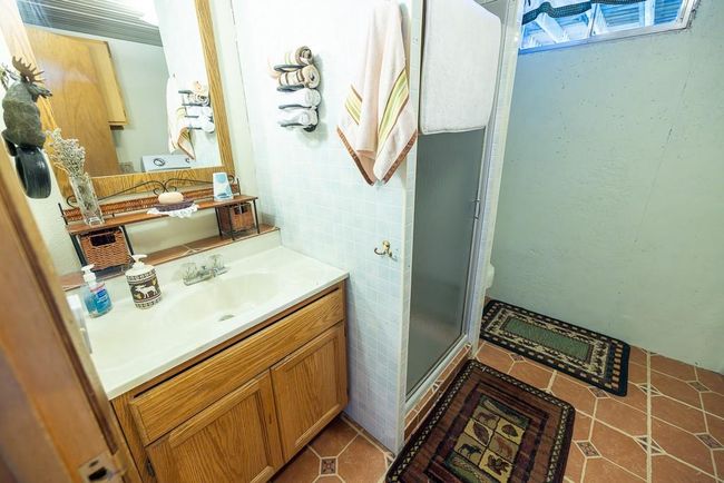 Bathroom with vanity, an enclosed shower, tile patterned floors, tile walls, and toilet | Image 21