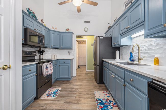 Kitchen featuring appliances with stainless steel finishes, a sink, blue cabinetry, light wood-type flooring, and a towering ceiling | Image 18
