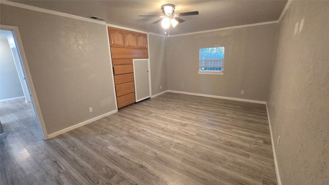 Unfurnished bedroom with wood finished floors, ornamental molding, and ceiling fan | Image 9