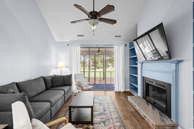 Living area with a ceiling fan, a fireplace with raised hearth, wood finished floors, and high vaulted ceiling | Image 10