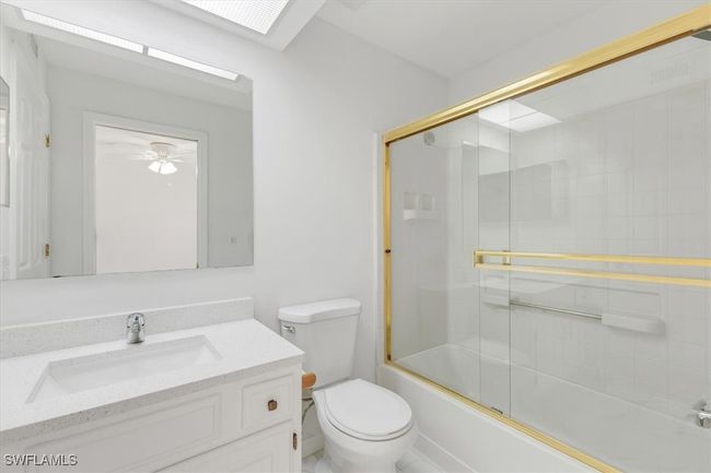 Full bathroom with vanity, combined bath / shower with glass door, tile patterned flooring, and toilet | Image 8