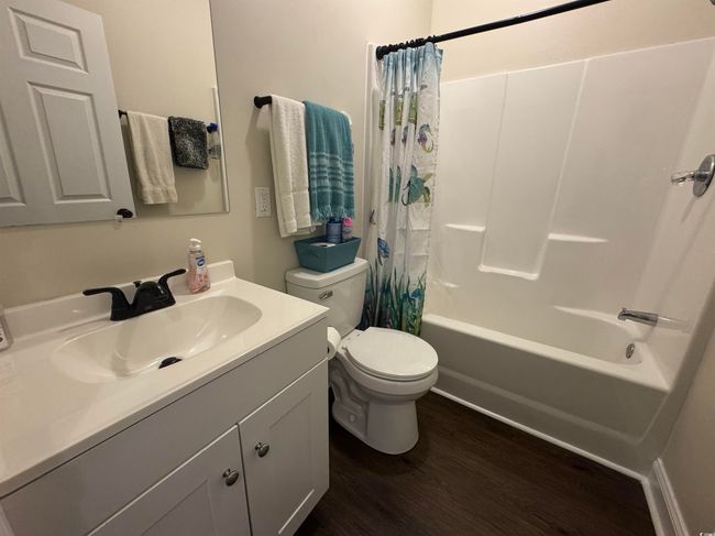 Bathroom featuring wood finished floors, toilet, shower / bath combination with curtain, and vanity | Image 12