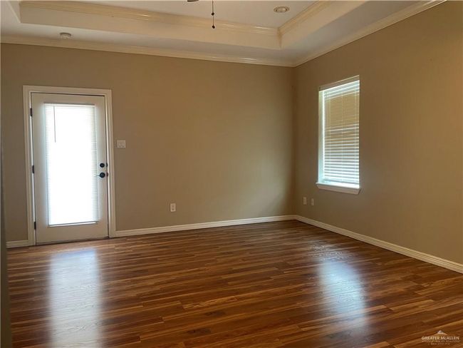 Unfurnished room with a raised ceiling, dark wood-type flooring, and crown molding | Image 4