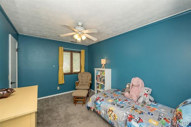 Carpeted bedroom featuring ceiling fan, a textured ceiling, crown molding, and baseboards | Image 25