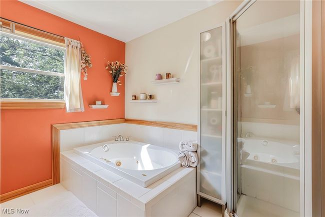 Full bath featuring a jetted tub, a shower with shower door, and tile patterned flooring | Image 37