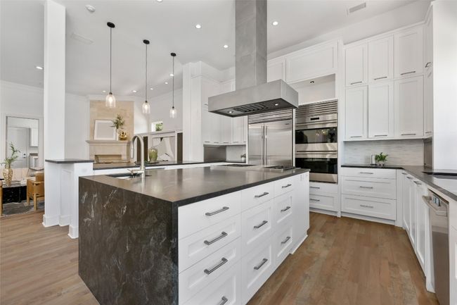 Kitchen featuring island range hood, dark countertops, a sink, appliances with stainless steel finishes, and ornamental molding | Image 9