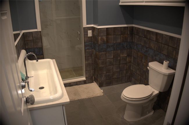 Bathroom with a shower stall, toilet, and tile walls | Image 7