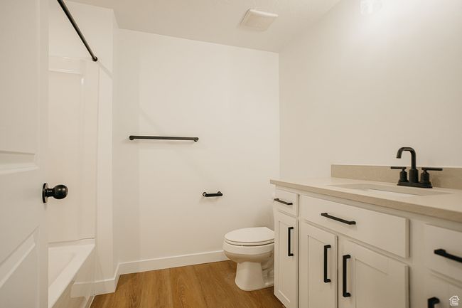 Full bath featuring vanity, wood finished floors, toilet, bathtub / shower combination, and baseboards | Image 42