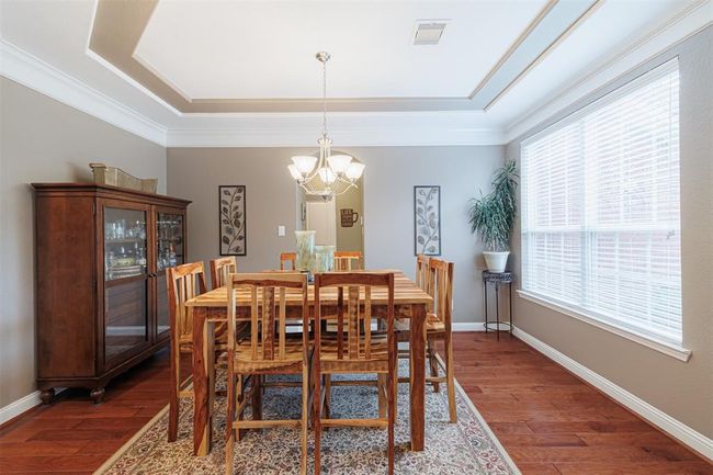 Formal dining room with tray ceiling, crown molding and wood flooring. | Image 11