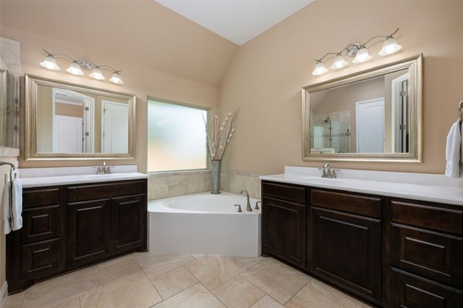 Bathroom with vaulted ceiling, a bath, two vanities, and tiled shower | Image 21