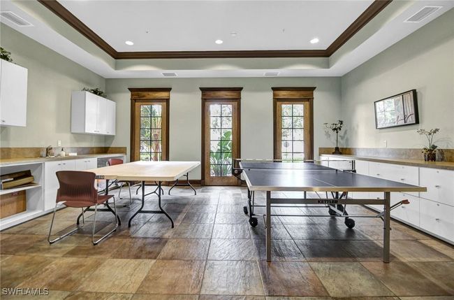 Game room featuring a tray ceiling, crown molding, healthy amount of natural light, recessed lighting, and stone finish flooring | Image 46