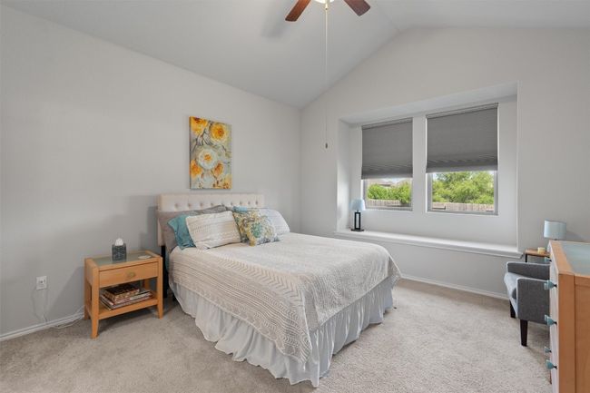 A serene primary suite complete with a high vaulted ceiling, a window seat for reading, and a ceiling fan. | Image 15