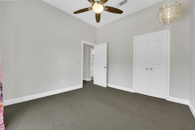 Unfurnished bedroom with dark colored carpet, a closet, a ceiling fan, and high vaulted ceiling | Image 22