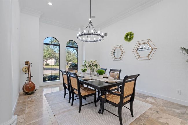 Another view of the dining room, showcasing the exquisite chandelier and columns that frame the space, with natural light enhancing the welcoming atmosphere. | Image 16