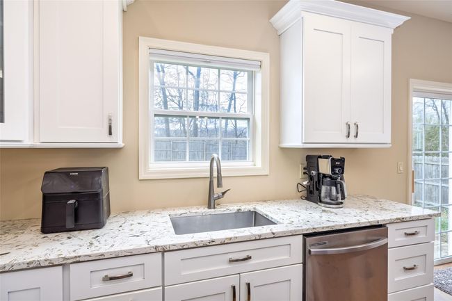 Kitchen featuring white cabinets, stainless steel dishwasher, light stone countertops, and a sink | Image 13