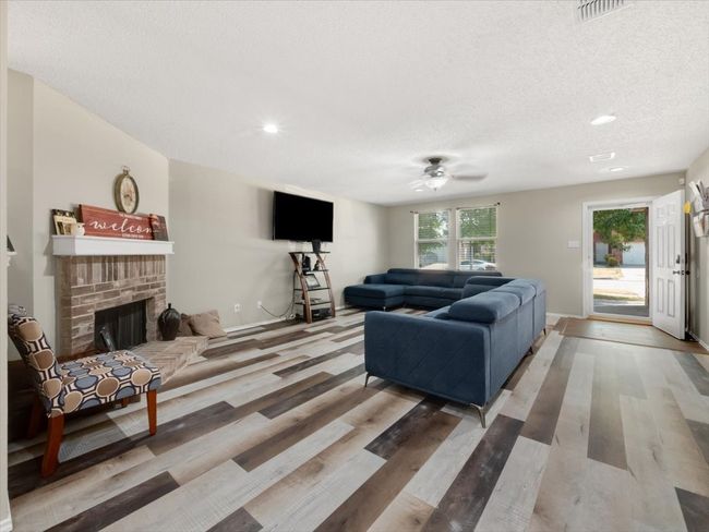 Living room featuring a brick fireplace, a textured ceiling, hardwood / wood-style flooring, and ceiling fan | Image 6