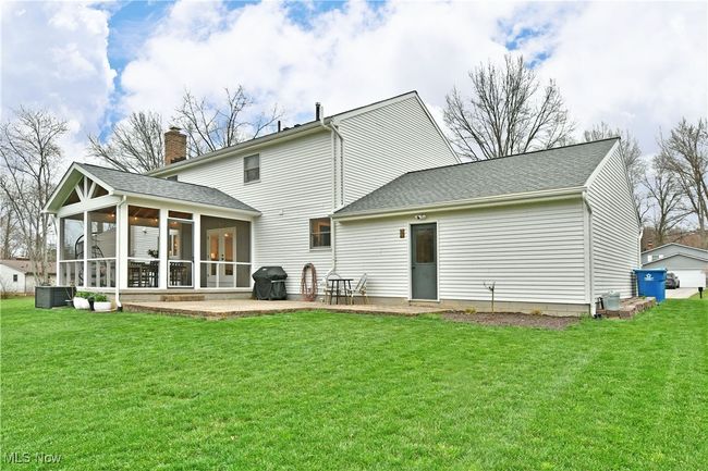 Back of house featuring a sunroom, a patio area, a lawn, a chimney, and roof with shingles | Image 6