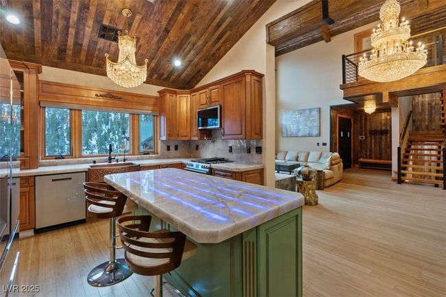Kitchen featuring tasteful backsplash, a chandelier, wood ceiling, appliances with stainless steel finishes, and high vaulted ceiling | Image 33
