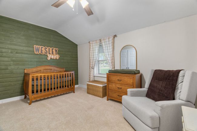 Carpeted bedroom featuring vaulted ceiling, wooden walls, and ceiling fan | Image 32