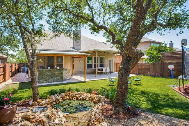 Rear view of property featuring a fenced backyard, a patio area, a shingled roof, and stone siding | Image 28