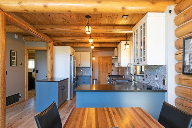 Kitchen with freestanding refrigerator, a sink, a peninsula, dark countertops, and light solid wood flooring | Image 10