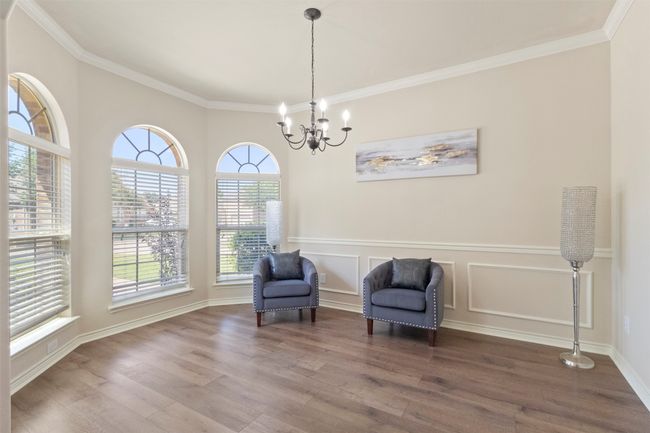 Sitting room with wood finished floors, a chandelier, ornamental molding, a wainscoted wall, and baseboards | Image 6