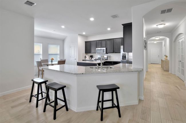 Kitchen with appliances with stainless steel finishes, a sink, arched walkways, a breakfast bar, and recessed lighting | Image 9