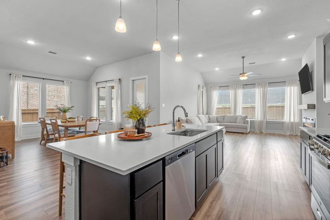 Kitchen featuring lofted ceiling, stainless steel appliances, an island with sink, pendant lighting, and open floor plan | Image 14