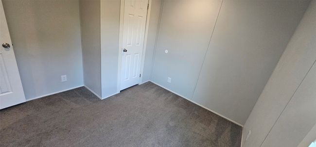 Unfurnished bedroom with dark colored carpet and baseboards | Image 6