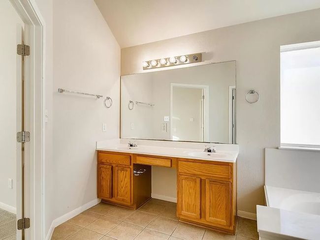 Full bath with double vanity, tile patterned flooring, a tub to relax in, vaulted ceiling, and baseboards | Image 18