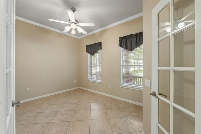 To the right of the entry is a private study featuring crown molding and elegant French doors. This versatile space is perfect for a home office or quiet reading area also featuring a convenient ceiling fan. | Image 9