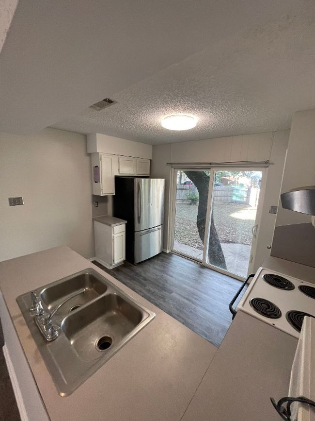 Kitchen featuring freestanding refrigerator, white range with electric cooktop, dark wood-type flooring, white cabinetry, and a textured ceiling | Image 12
