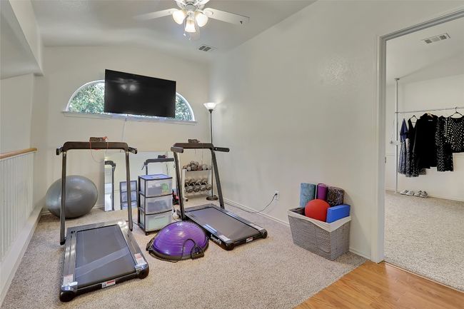 Exercise area featuring ceiling fan, wood finished floors, vaulted ceiling, and carpet | Image 18