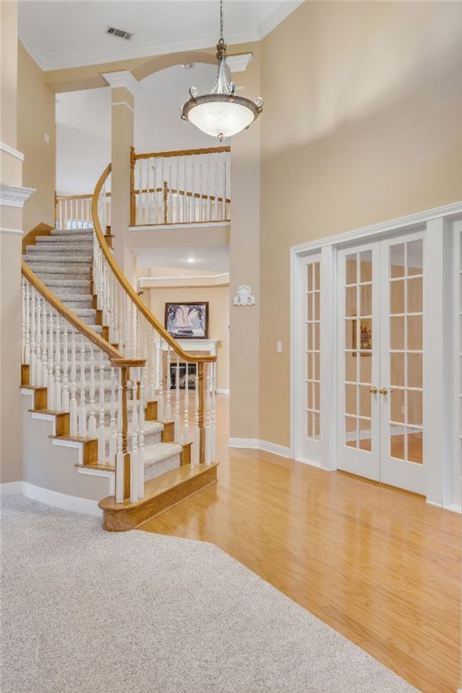 Entrance foyer with a towering ceiling, crown molding, french doors, stairway, and wood finished floors | Image 7