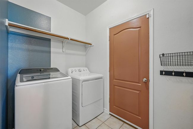 Laundry area with washing machine and dryer and light tile patterned floors | Image 12