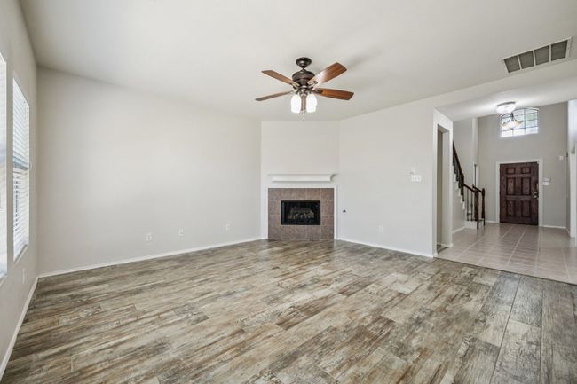 Unfurnished living room with wood finished floors, a ceiling fan, a gaslog fireplace, a chandelier, and stairway | Image 8