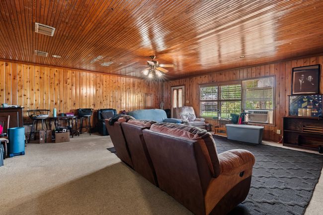 Living room with wooden walls, visible vents, a ceiling fan, wooden ceiling, and carpet flooring | Image 26
