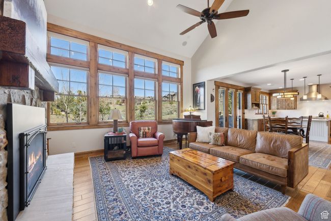 Living area with light wood finished floors, ceiling fan, a glass covered fireplace, and high vaulted ceiling | Image 5