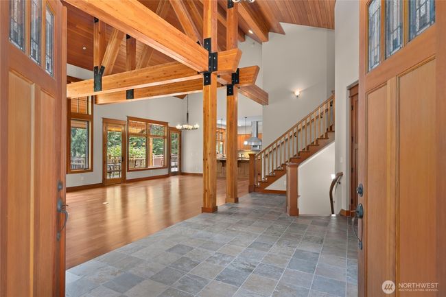 Double doors with stain glass that open up to this great room with incredible beams and a huge stone fireplace. | Image 8