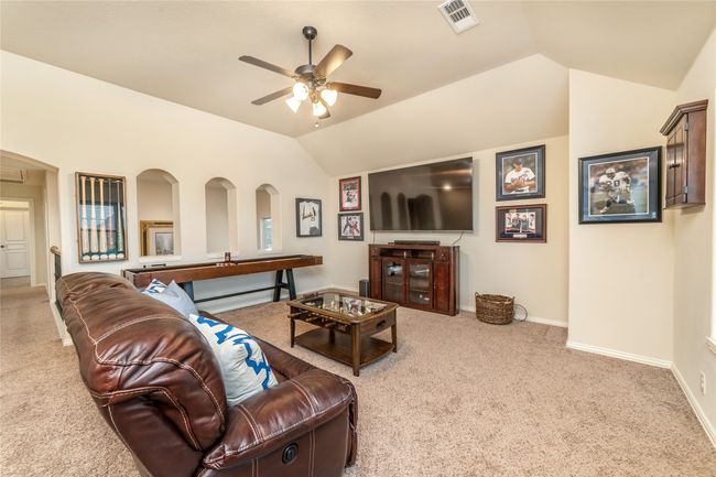 Living room with carpet, a ceiling fan, vaulted ceiling, and baseboards | Image 22
